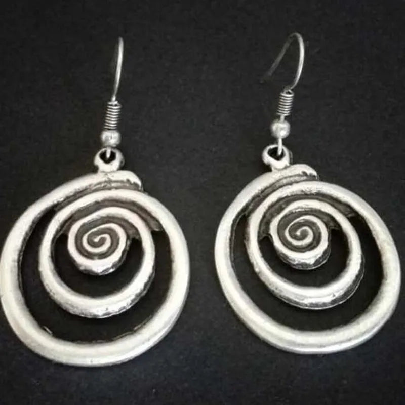 Close-up of a pair of silver geometric spiral earrings with a distressed vintage finish.
