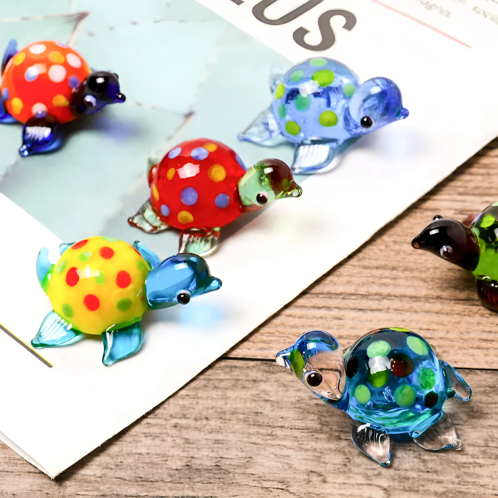 Set of six geometric glass turtle ornaments in various colour combinations on a desktop.