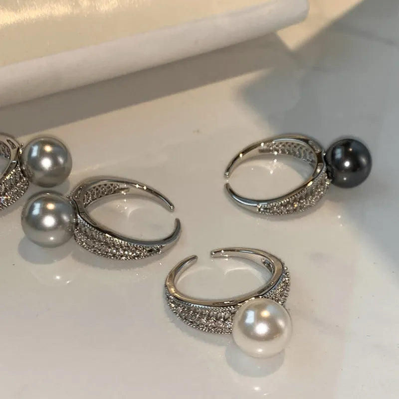 Copper geometric open ring with a black pearl, shown on a woman's index finger.