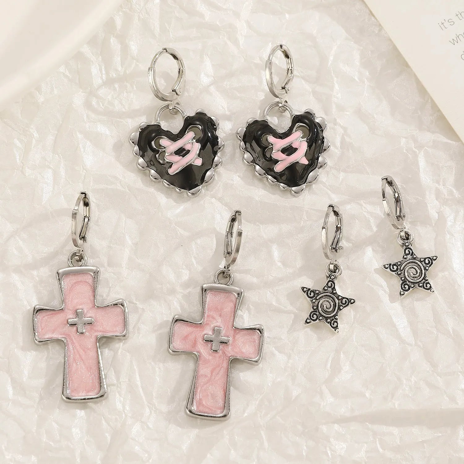 Women's alloy earrings with cross and heart designs in white, black, and silver colour options.