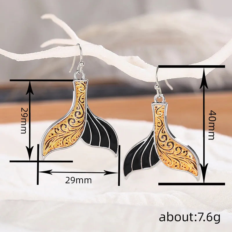 Women's retro-style fishtail-shaped alloy earrings with a whale decoration in white gold colour.