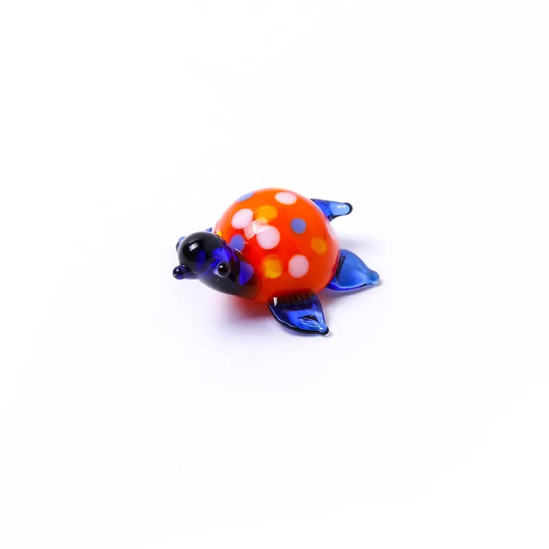 Set of six geometric glass turtle ornaments in various colour combinations on a desktop.
