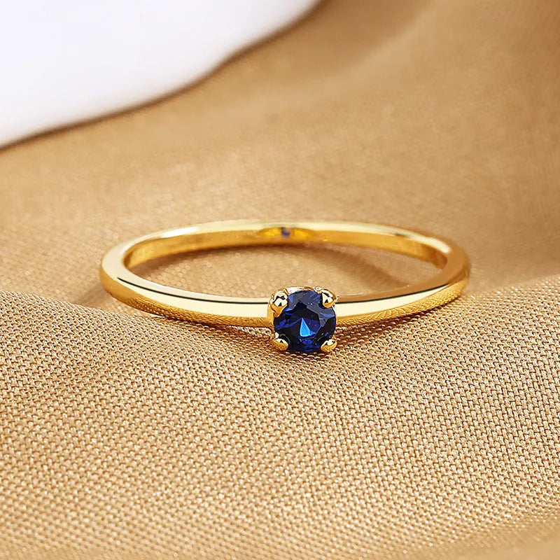 Simple geometric copper ring with a single round diamond, shown in blue, green, red, and white colour options.