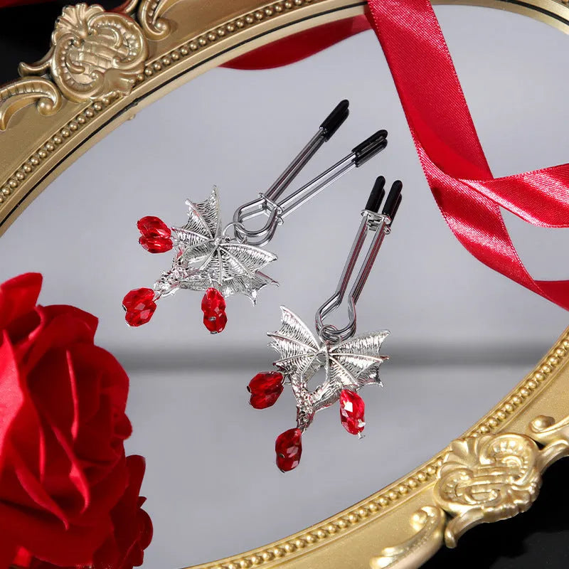 Silver alloy bat-shaped nipple clamp with ruby details and adjustable rubber-padded mechanism.