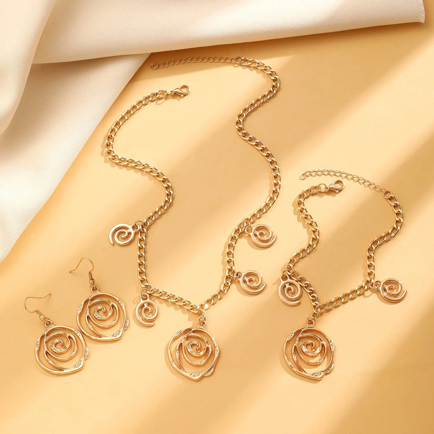 Spiral donut jewellery set with necklace, bracelet and earrings showing geometric circle designs in gold and silver finishes