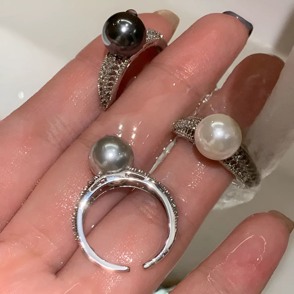 Copper geometric open ring with a black pearl, shown on a woman's index finger.