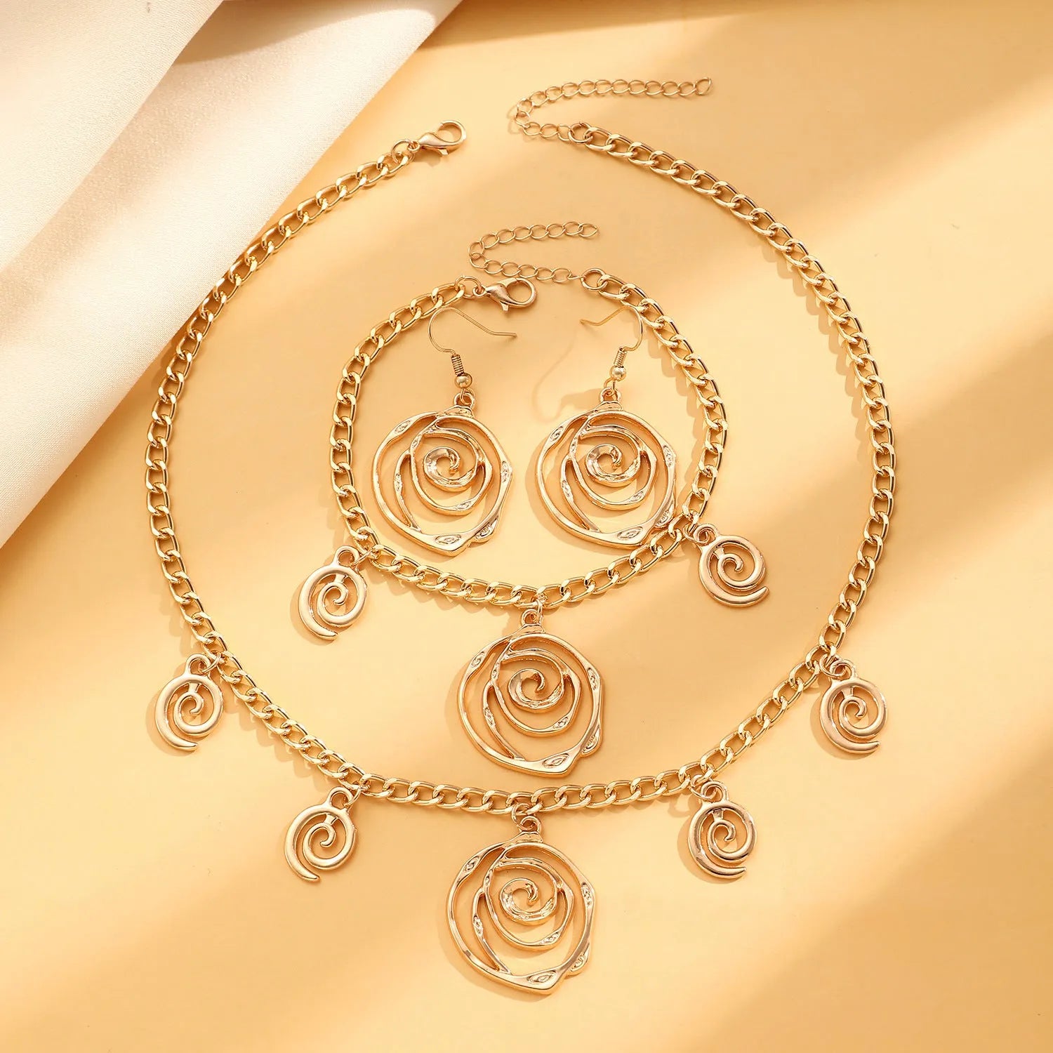Spiral donut jewellery set with necklace, bracelet and earrings showing geometric circle designs in gold and silver finishes