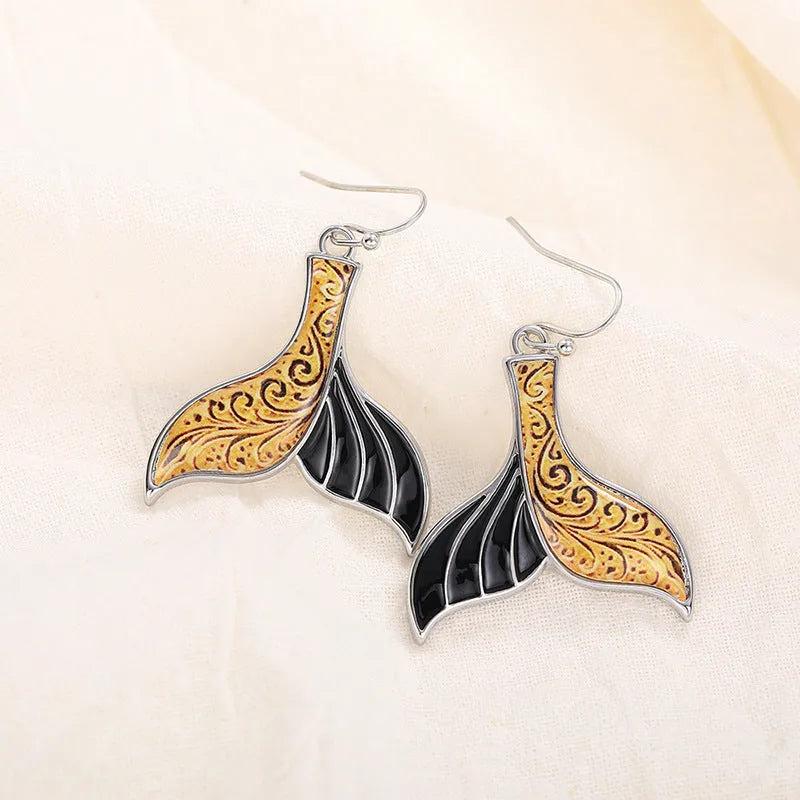 Women's retro-style fishtail-shaped alloy earrings with a whale decoration in white gold colour.