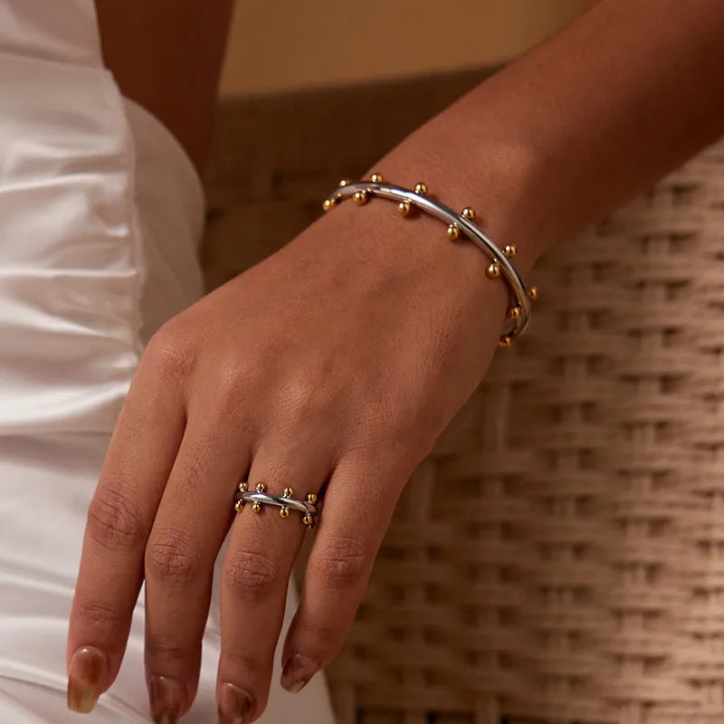 Stainless steel C-shaped bean bead with textured rivet surface in gold colour