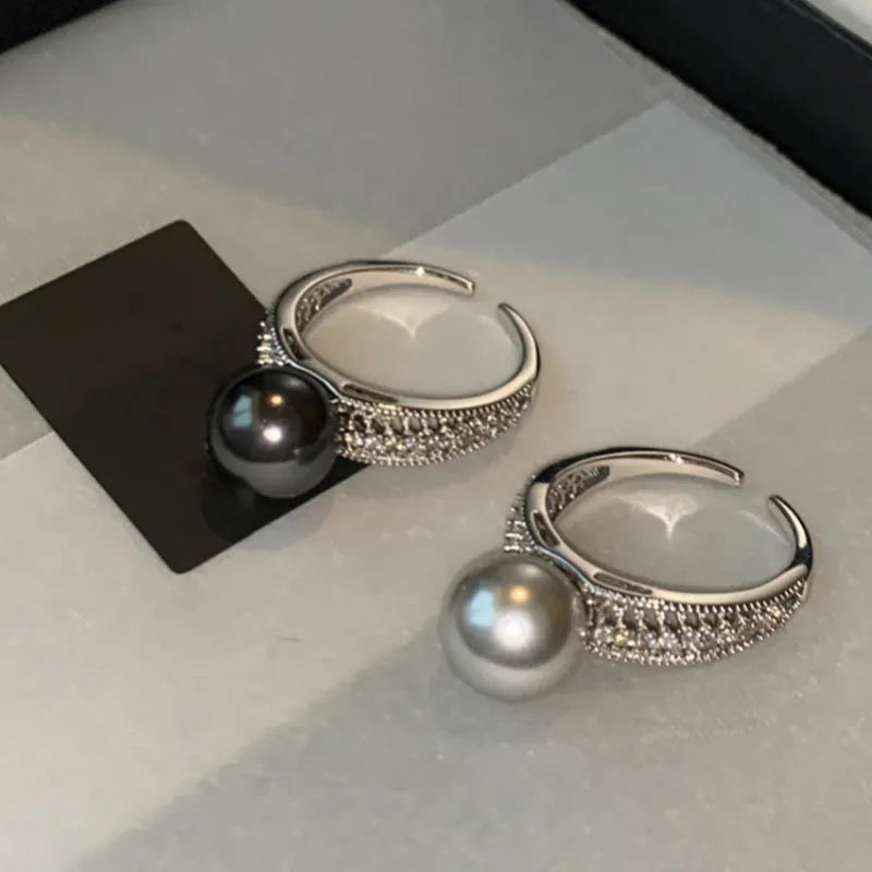 Copper geometric open ring with a black pearl, shown on a woman's index finger.