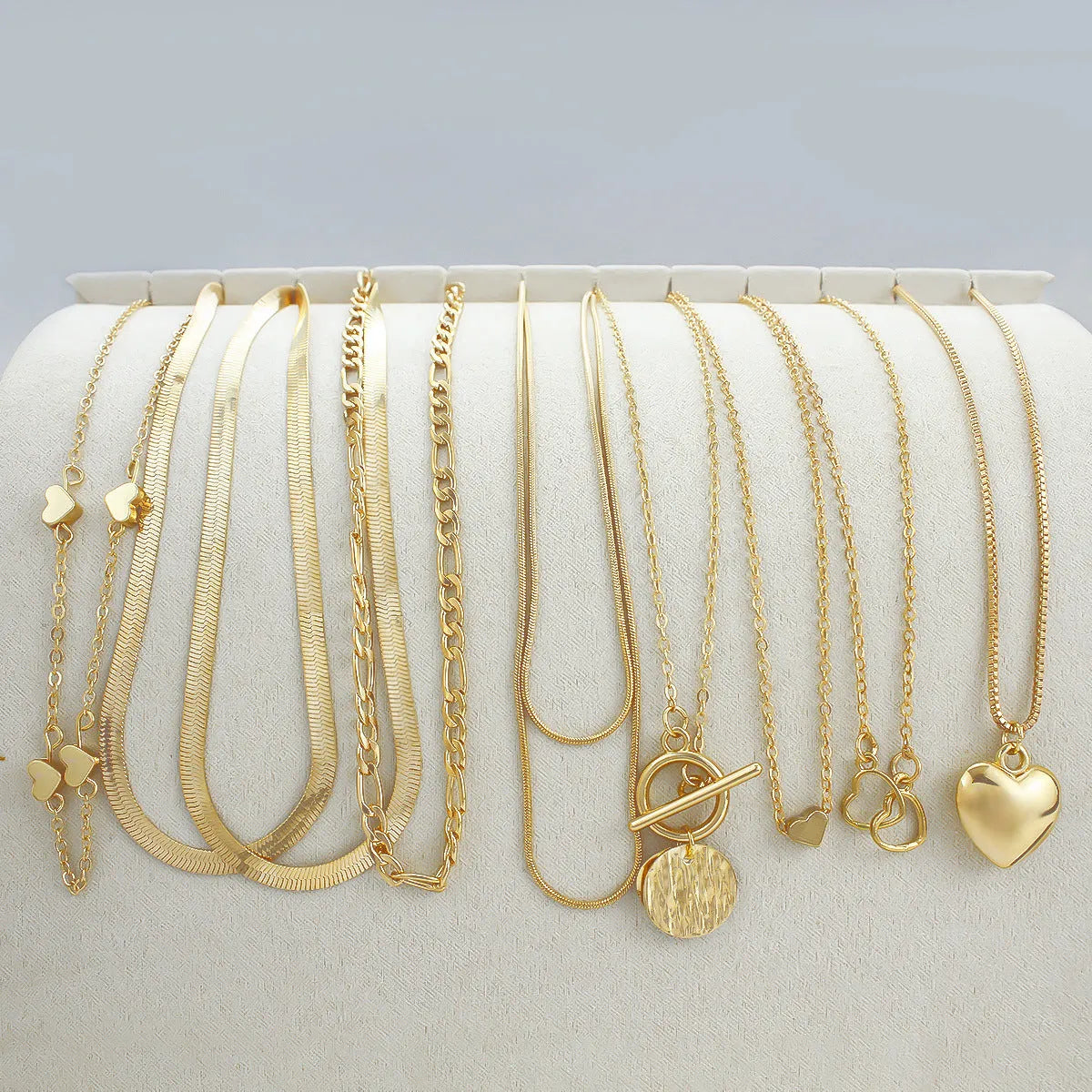 10 gold necklaces with snake bone chains and alloy pendants arranged in jewellery set