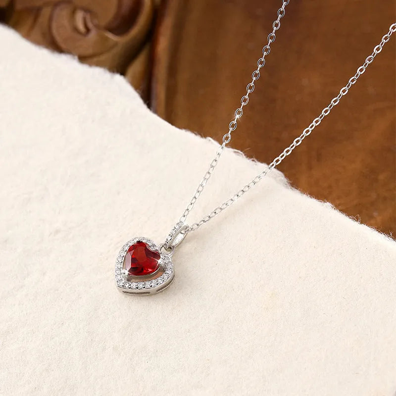 Close-up of a sterling silver heart pendant necklace with an inlaid amethyst gemstone on a cross chain.