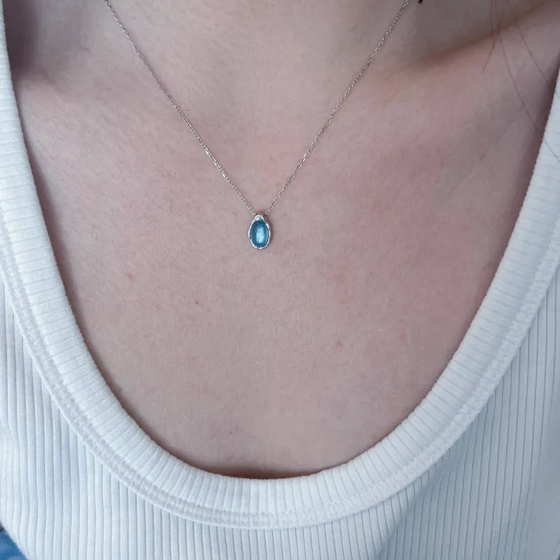 Navy blue water drop pendant necklace with adjustable chain on neutral background