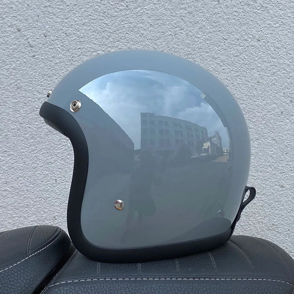 Cement grey retro half motorcycle helmet with glass fibre shell on a plain background.
