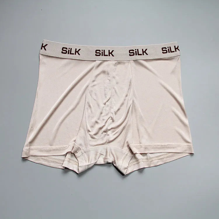 Man wearing loose-fitting mid-waist silk shorts in navy blue, silver grey, or skin colour.