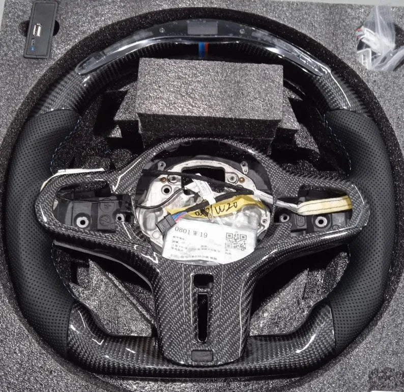 Black carbon fibre BMW sports steering wheel with integrated LED multifunctional display.