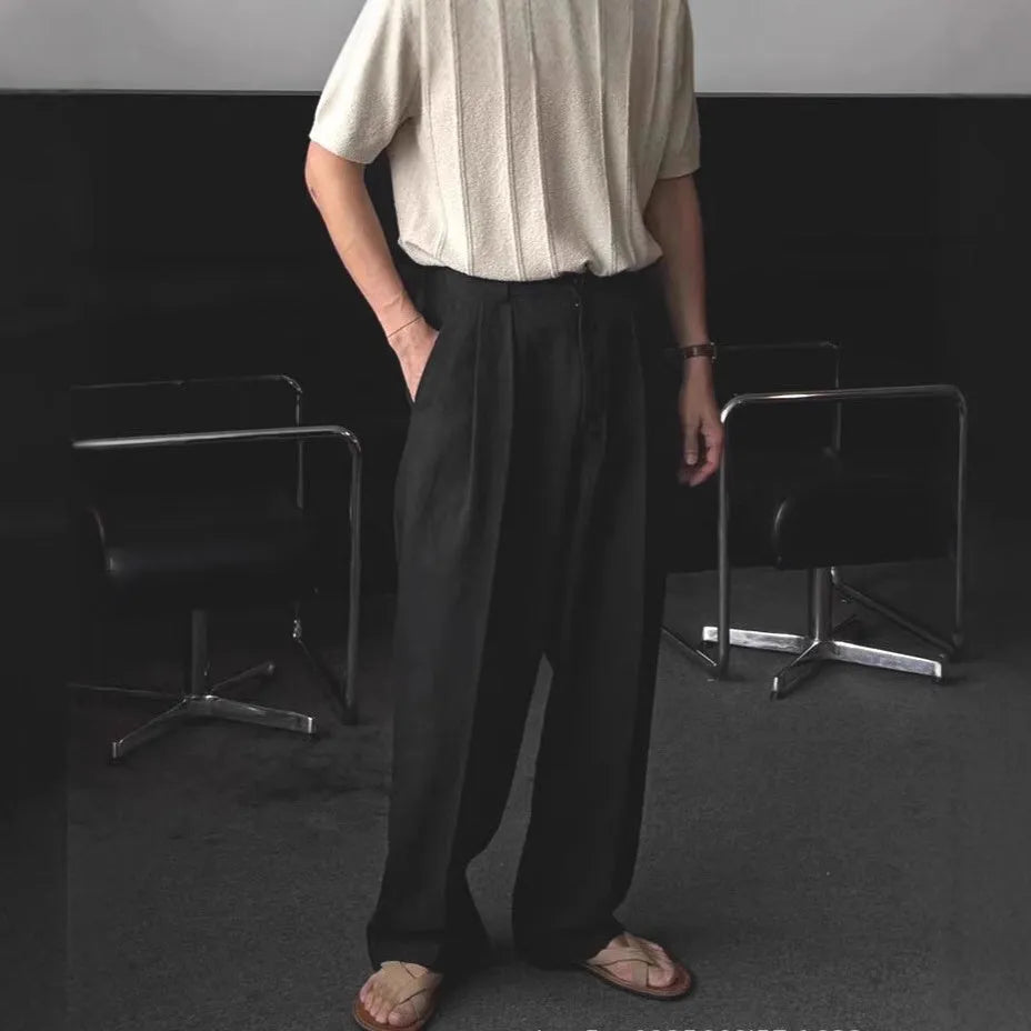 Men's apricot coloured loose-fit cotton linen trousers with a pencil leg and elastic waist on a neutral background.