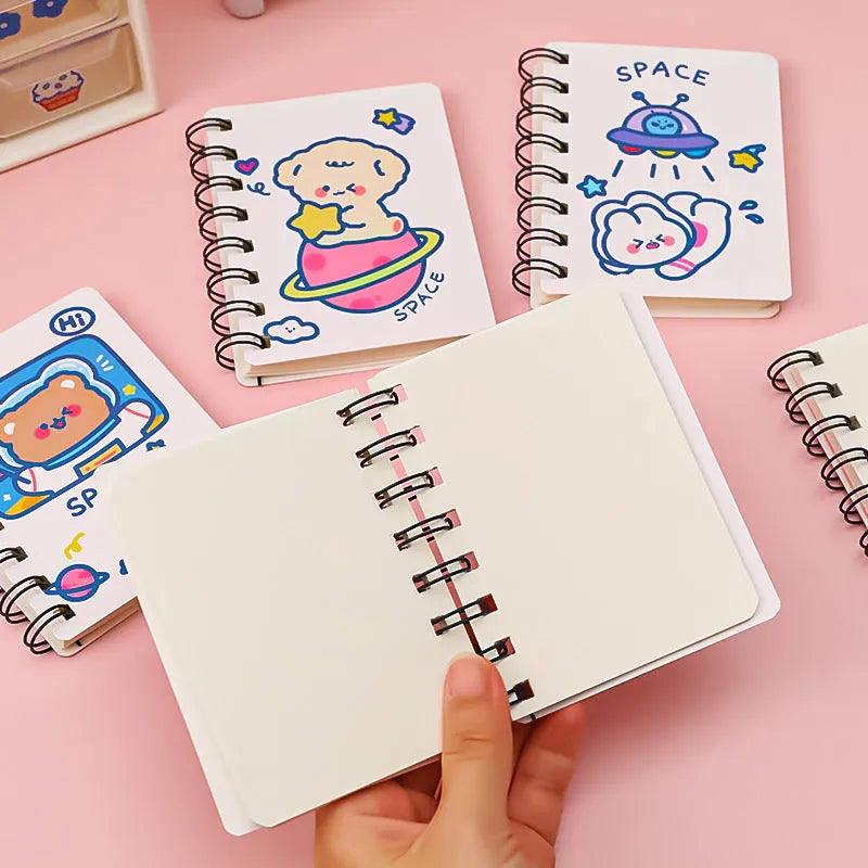 Small astronaut-themed flipper notebook showing one of four cover designs: Astronaut Bear, Planet Teddy, Space Cat, or UFO.