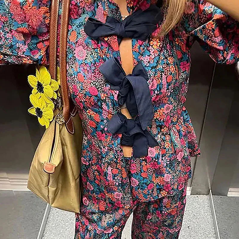 Women's floral print two-piece trouser suit with puff sleeve top and matching trousers.