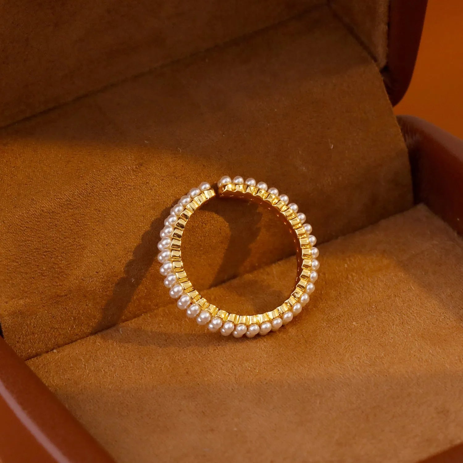 Gold geometric open ring for women with a pearl centre on a white background.
