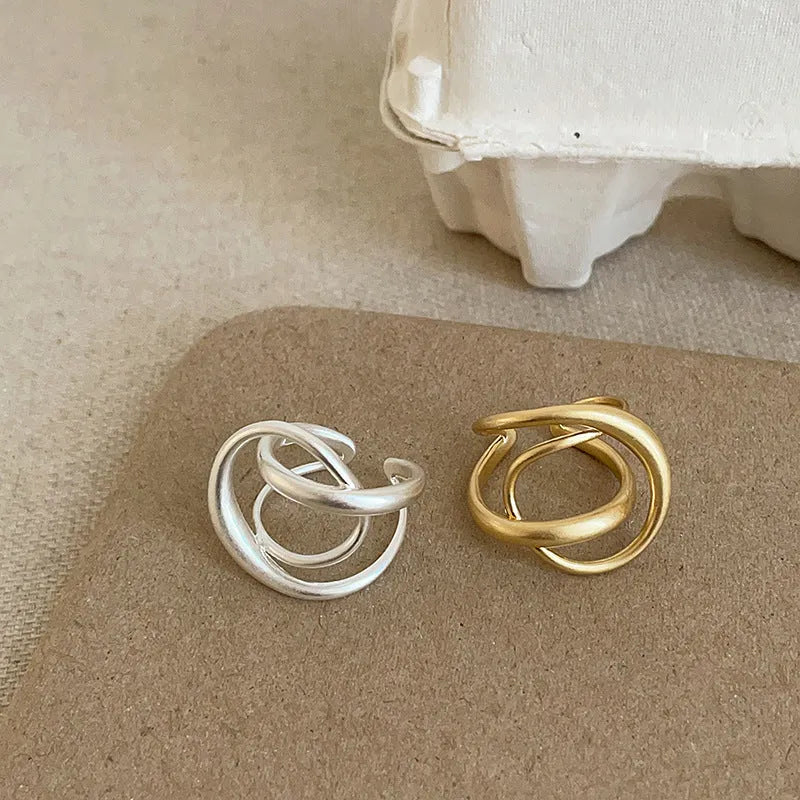 Geometric open ring with three-dimensional interlaced metal and matte electroplated finish in gold or silver colour