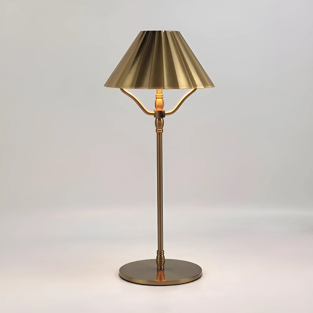Gold-coloured alloy desk lamp with a fabric shade on a wooden desk.