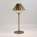Gold-coloured alloy desk lamp with a fabric shade on a wooden desk.