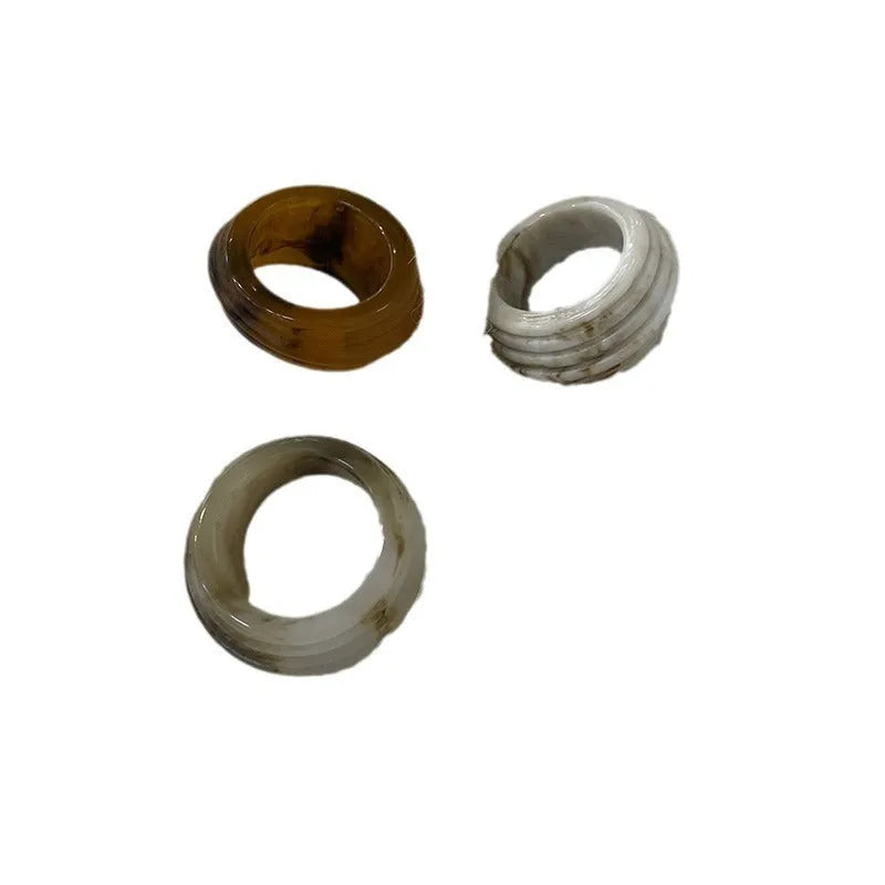 Chinese style irregular wide geometric resin ring in brown or white on display.