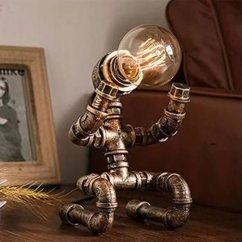 Industrial retro style table lamp made from iron pipes with a robot figure detail, in a vintage finish.