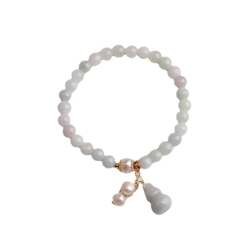 Close-up of a women's jade bracelet with a gourd motif, emerald jade insets, and pearl accents.