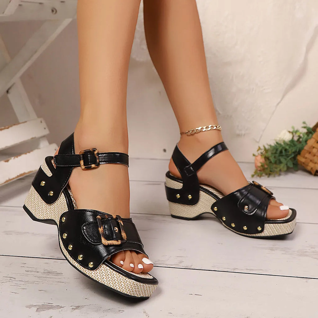 Women's black square-toe sandals with a chunky heel and metal buckle fastening on a white background.