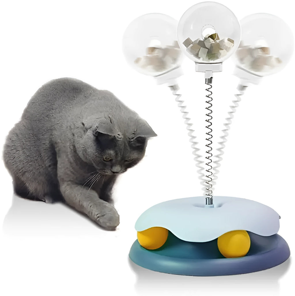 Blue and green interactive cat treat dispenser toy with a track ball on a wooden floor.