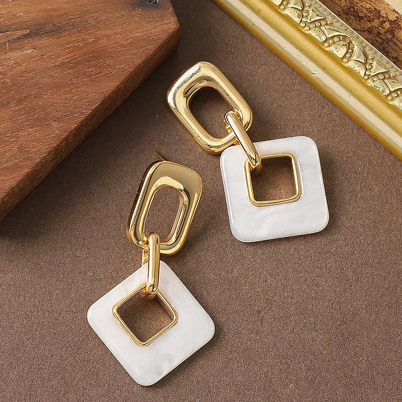 Pair of hollow geometric square copper earrings with chamfered corners in silver tone finish.