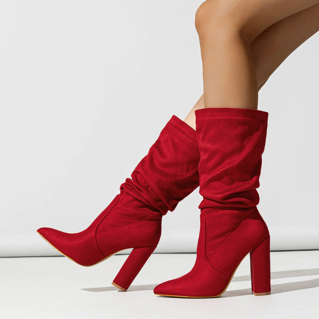Women's black suede high heel boots with a chunky heel and pointed toe, shown on a model.