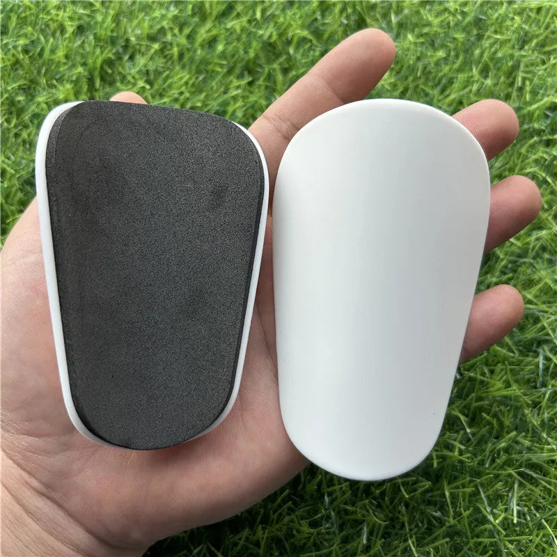 A pair of extra small mini plastic football shin guards, shown in either black or white.