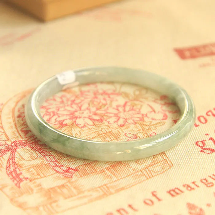 Green handmade geometric jade waxy bracelet with a 10mm bead on a black background.