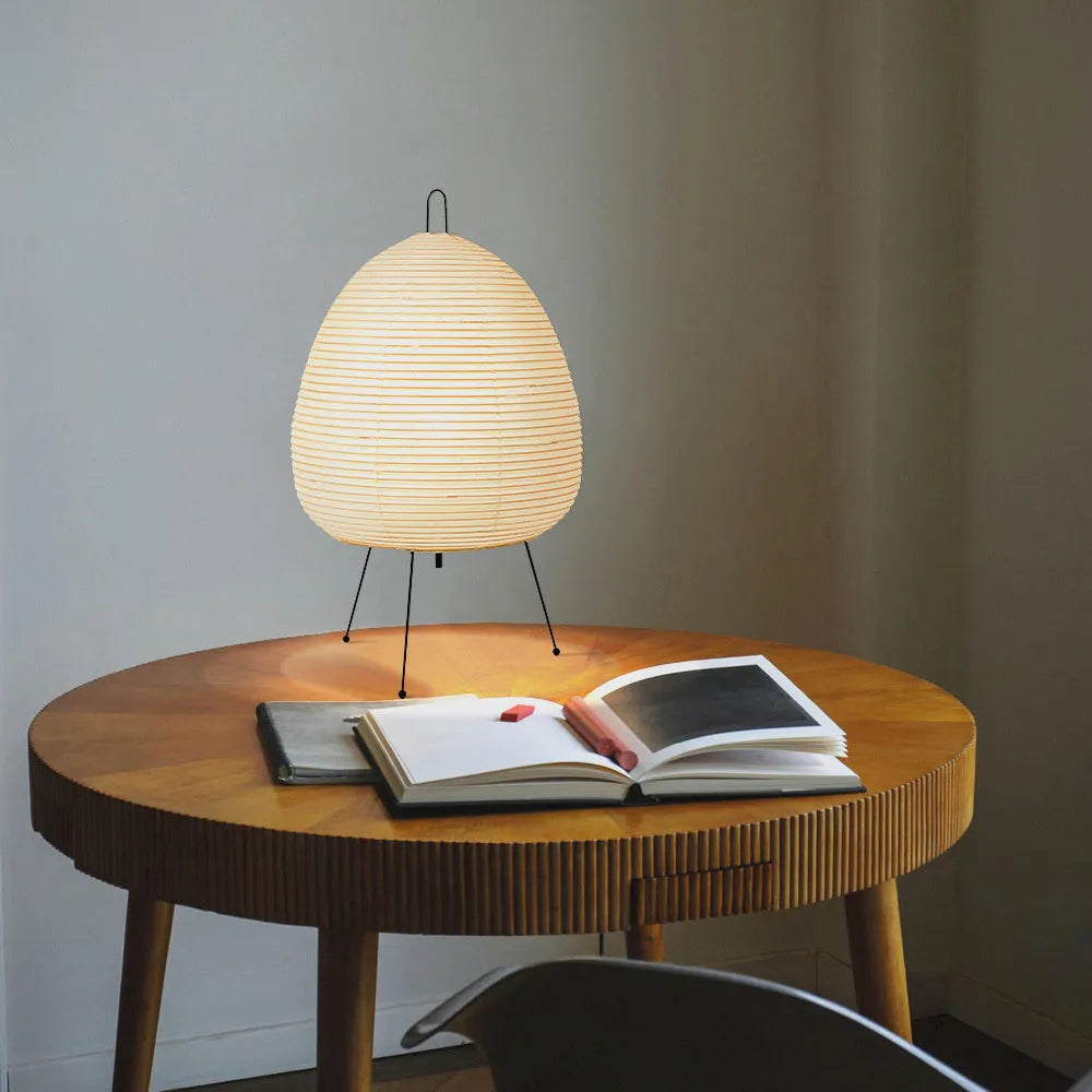 Japanese style handmade rice paper table lamp with an aluminium base on a wooden table.