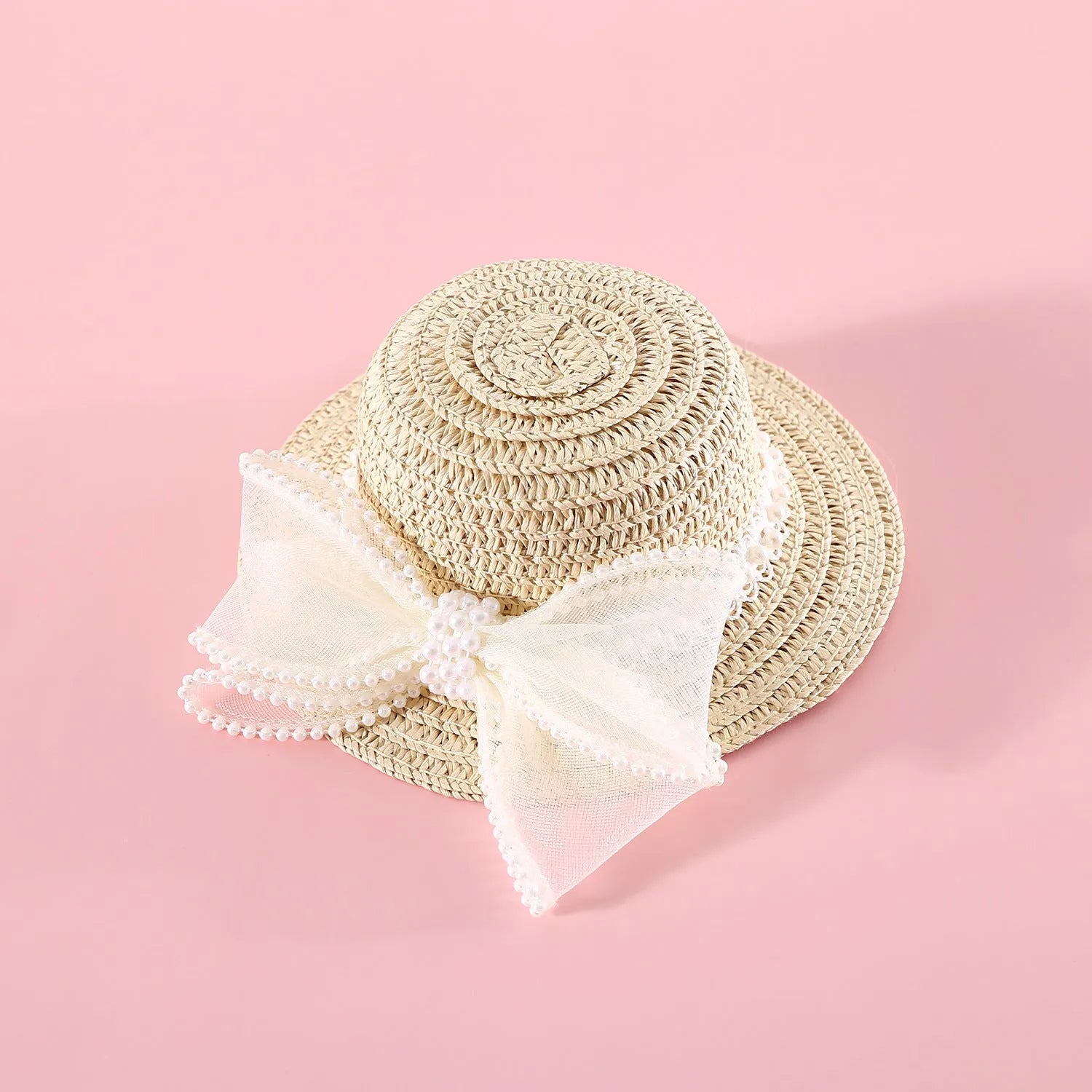 Cat wearing a woven straw hat with a pearl butterfly bow on its head.