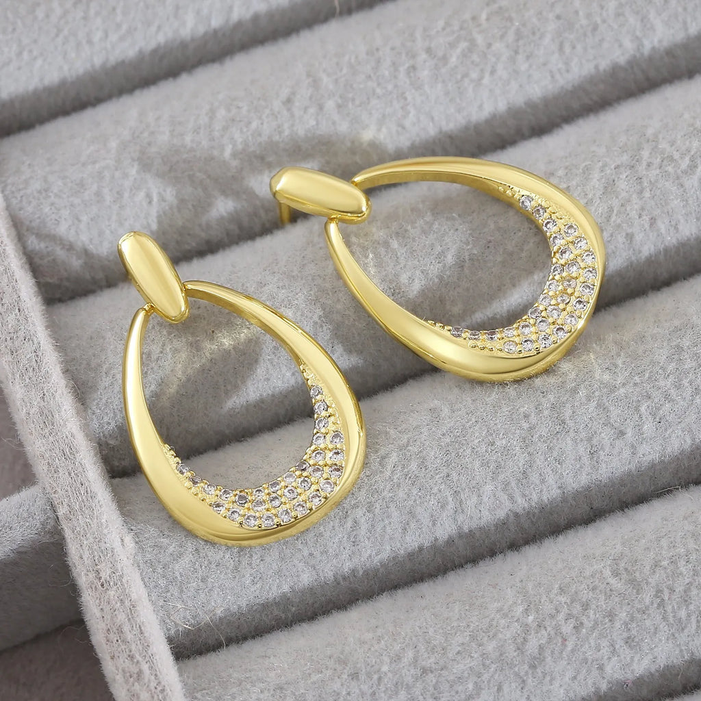 Women's yellow gold geometric drop-shaped earrings with ring design and zircon accents on a white background.