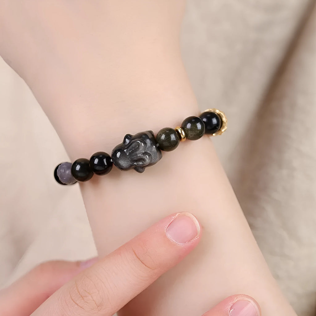 Handmade Chinese style bracelet with lying rabbit charm, grey agate bead, and brass on a black background.