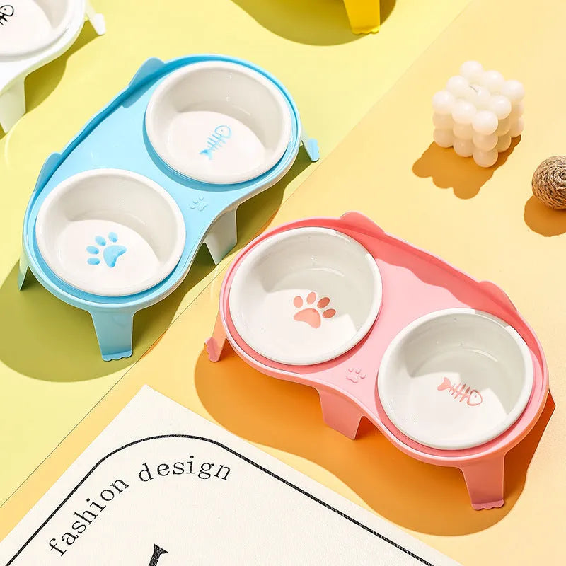 Blue ceramic cat food and water bowls on a white elevated stand with a storage hook.
