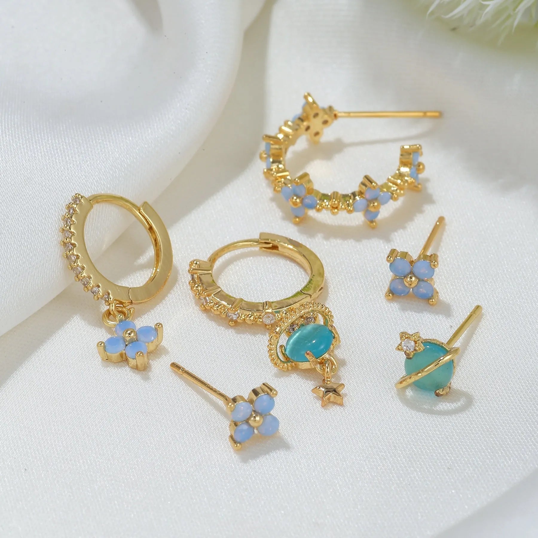Gold and silver flower shaped stud earrings with zircon mosaic accents on white background