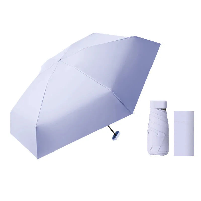 Six-fold manual umbrella in sky blue with capsule box storage, showing compact folded size and rubber handle