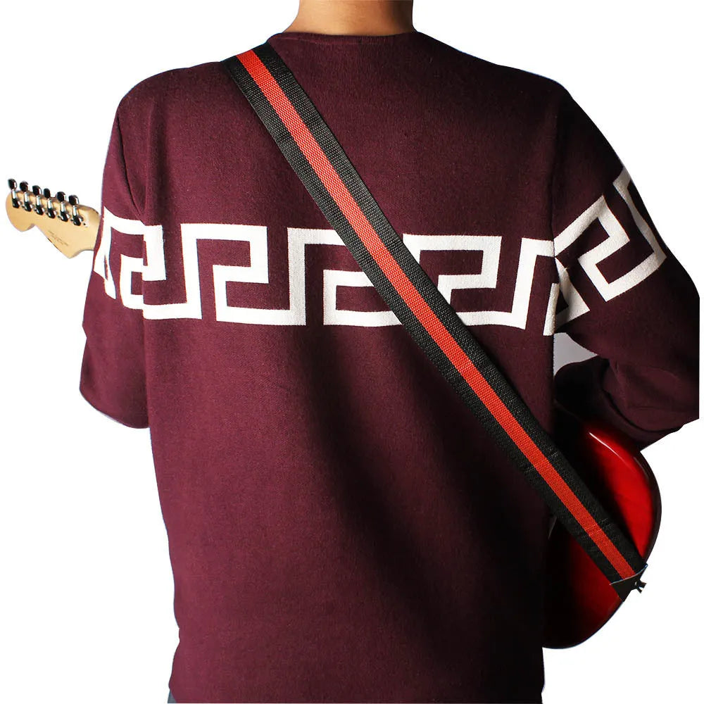 A woven crossbody guitar strap with a stripe pattern, shown attached to an electric guitar.