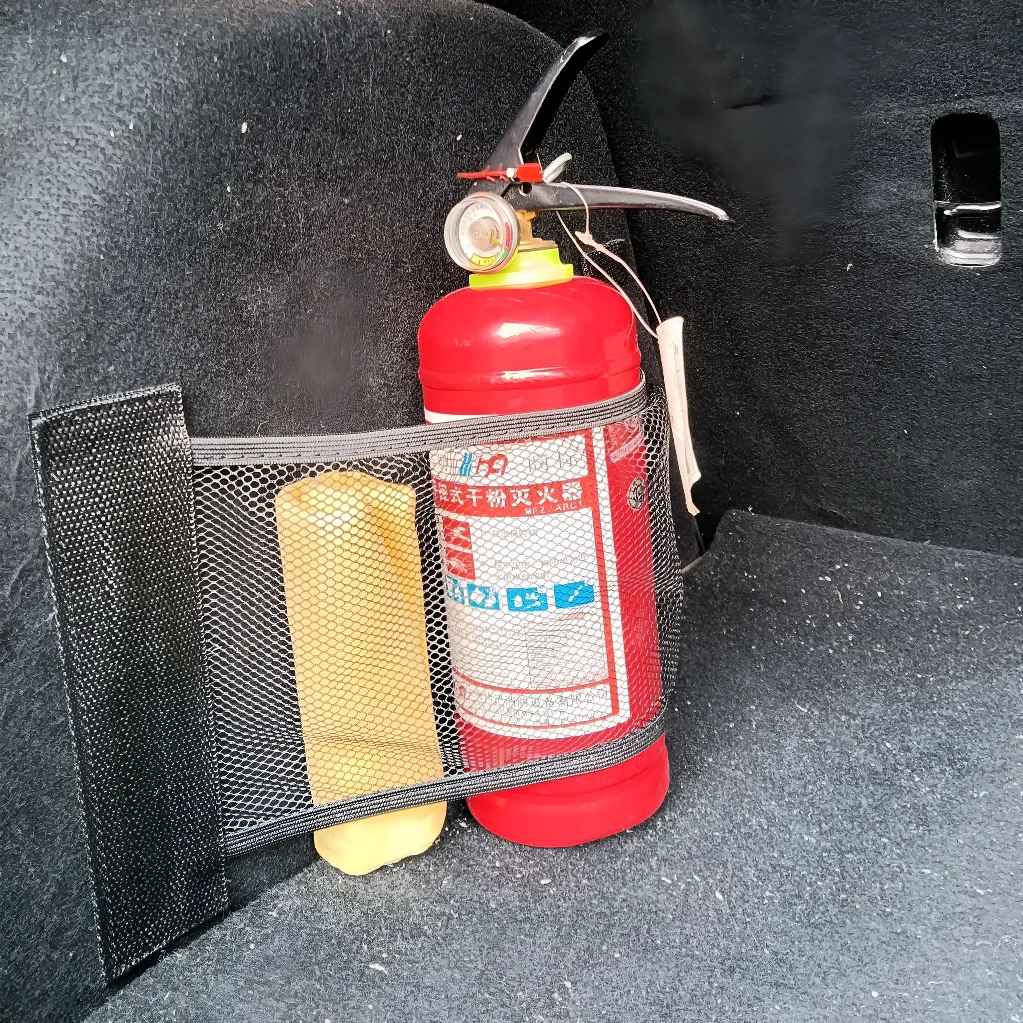 Elastic polyester car boot storage net shown with metal hooks and adhesive strips for organising loose items.