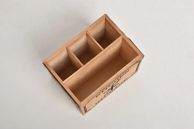 Open-top wooden kitchen storage box with internal grid divider for organising utensils.