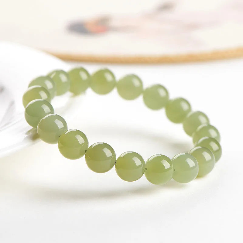 Polished Hetian jade ball bracelet in ice clear colour on a wrist, showing spherical beads.