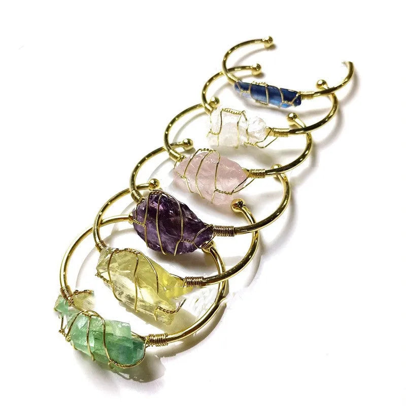 Natural rough crystal bracelet with gold geometric winding on a wrist, showing bohemian style.