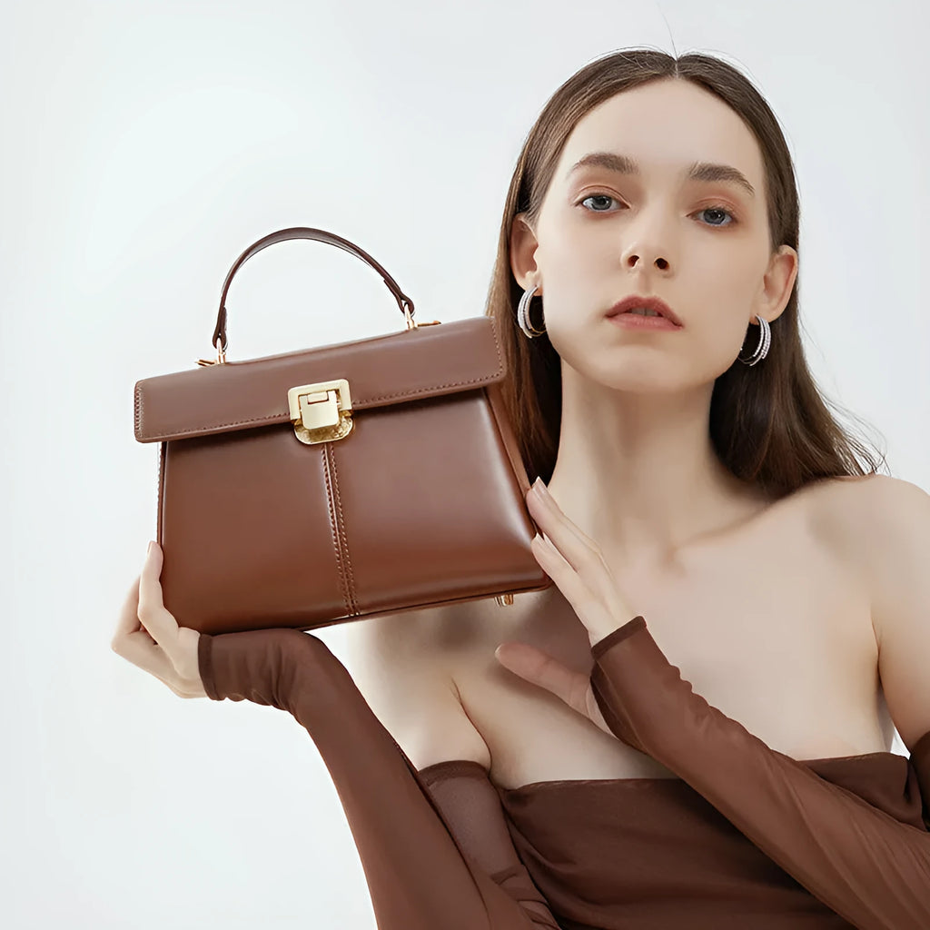 Black leather women's shoulder bag with vachette clasp showing horizontal square shape and adjustable strap