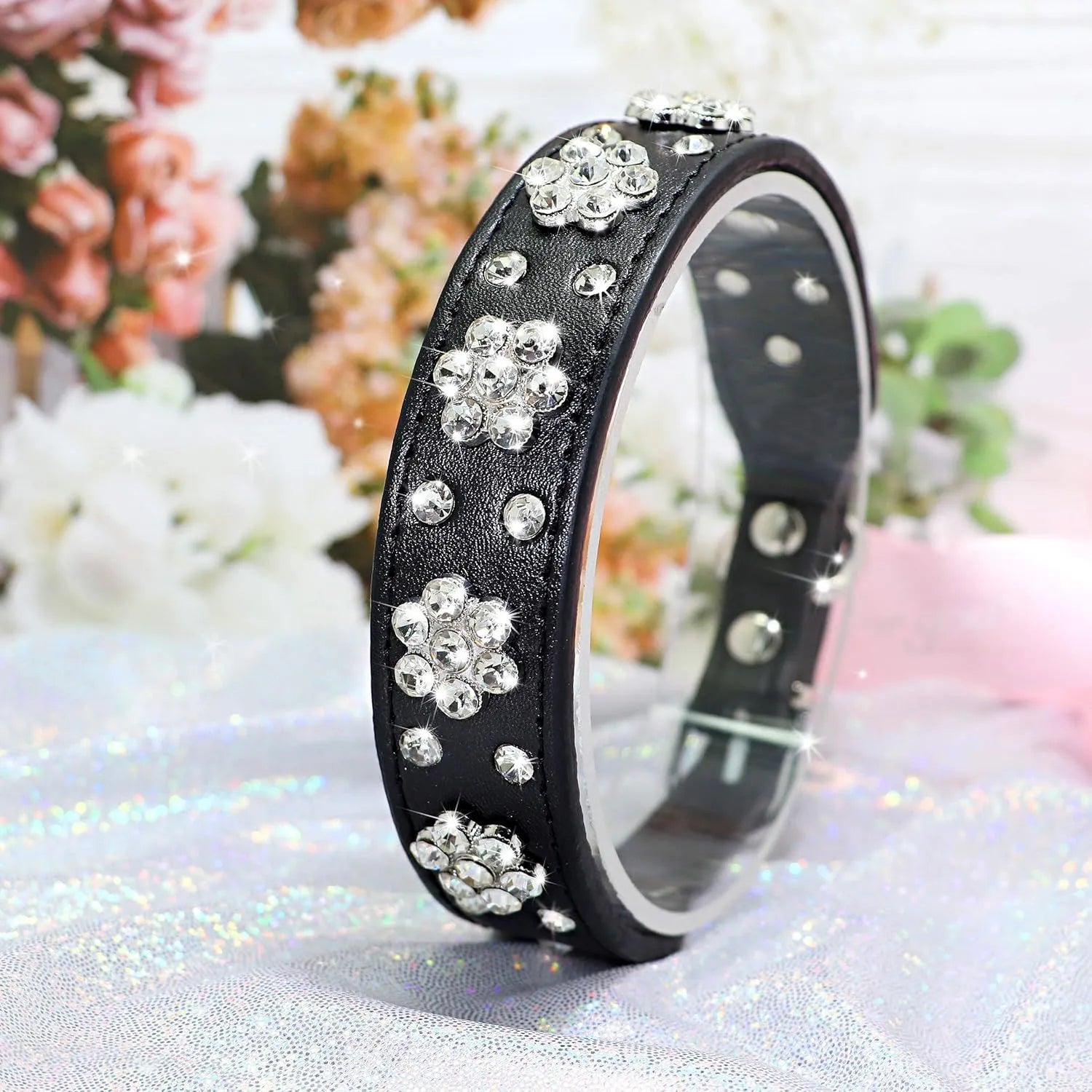 A pink PU leather dog collar studded with silver rhinestone flowers and a metal D-ring.